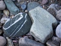 Dunkelgrauer Stein mit weißer Maserung umgeben von hellen Steinen